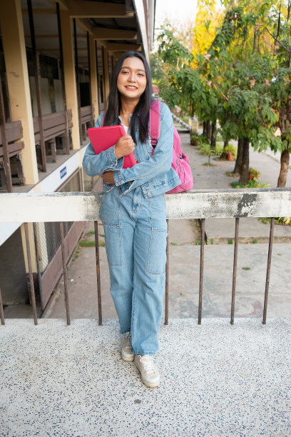 女学生拿着书包站在校园里。图片下载