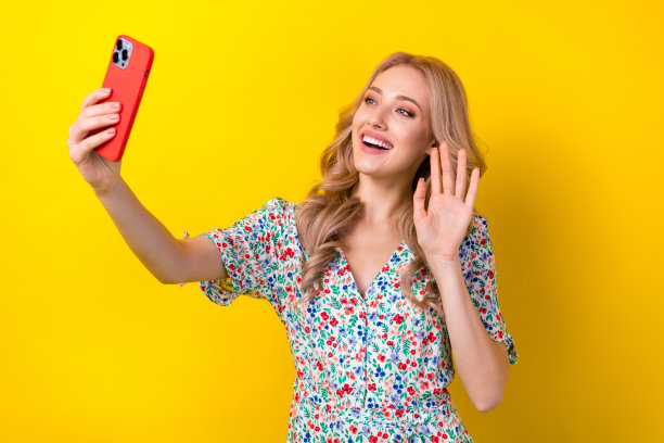 开朗迷人的女孩的照片，波浪发型，穿着时尚的衣服，和朋友聊天，在黄色背景上显示你好图片下载