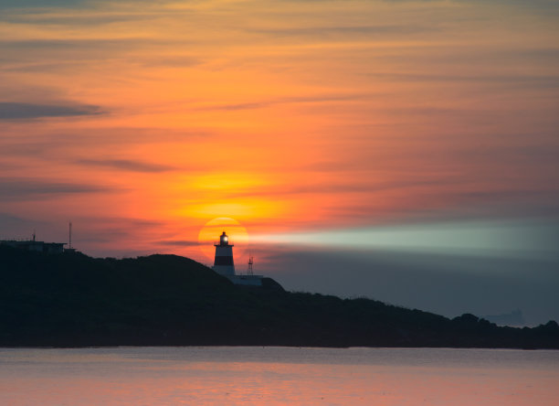 风力涡轮机的风扇在波光粼粼的海面上旋转。日落时的动态云。图片下载