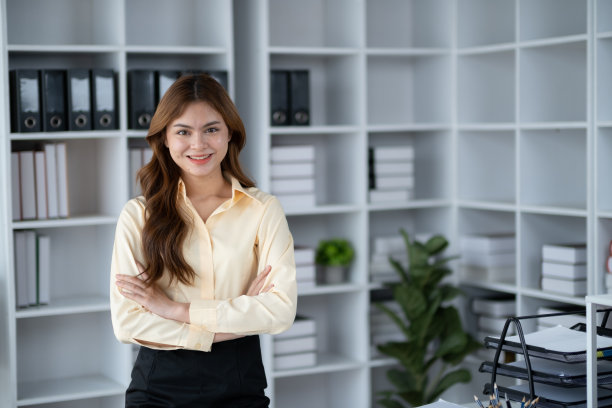在办公室工作时双臂交叉的迷人女商人。图片下载