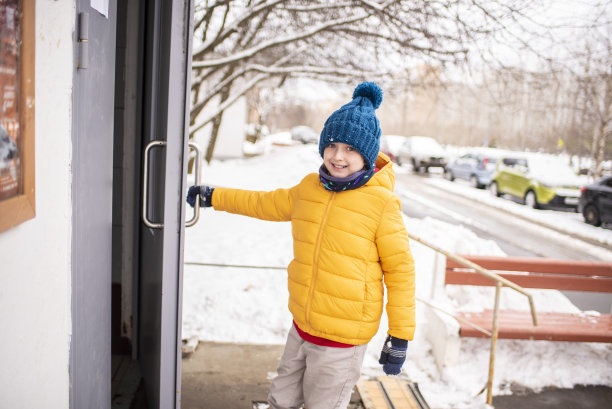 一个穿着鲜艳衣服的男孩在冬天打开大门，孩子在寒冷的天气里独自从学校回来图片下载