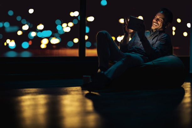 成功完成一天的工作后，年轻的商人坐在包椅上使用数码平板电脑图片下载