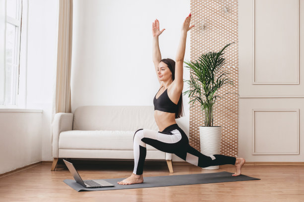年轻女子在家用笔记本电脑做瑜伽练习图片下载