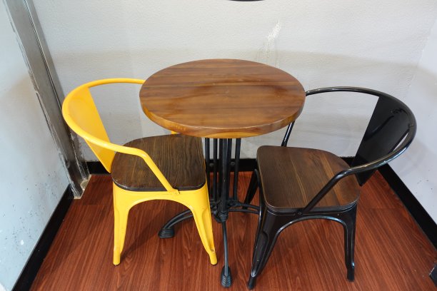 黄色椅子和黑色椅子，地板上的天然木桌图片下载