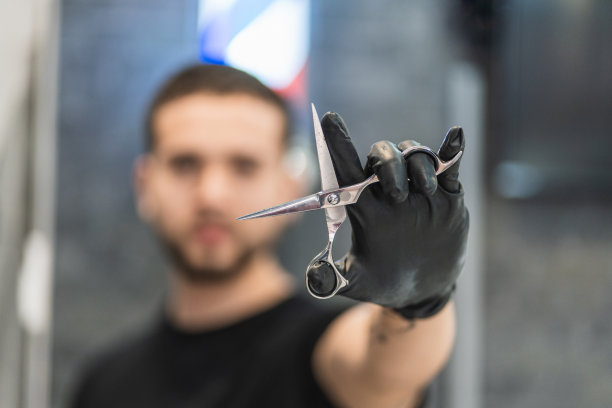 一个理发师在他的理发店里向镜头展示打开的剪刀的肖像。专注于刀具。图片下载