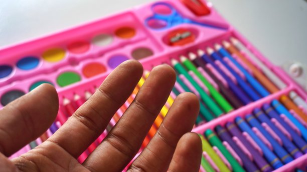 手持彩色铅笔或彩色粉彩整齐地安排一组彩色铅笔的背景图片下载