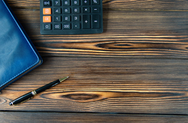 记事本，计算器，笔的俯视图。棕色木制背景。录音的地方。横幅。图片下载