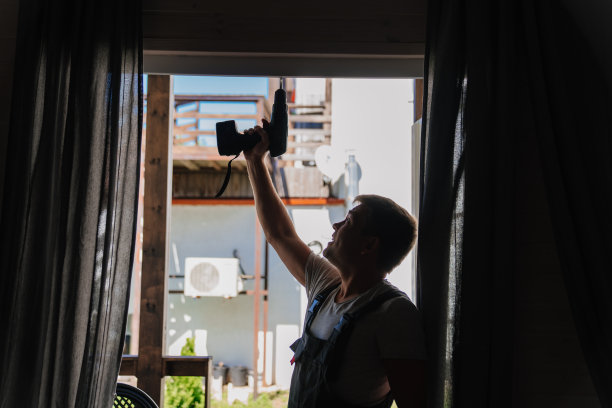 修理工的剪影正在修理阳台上的窗框或玻璃门。图片下载