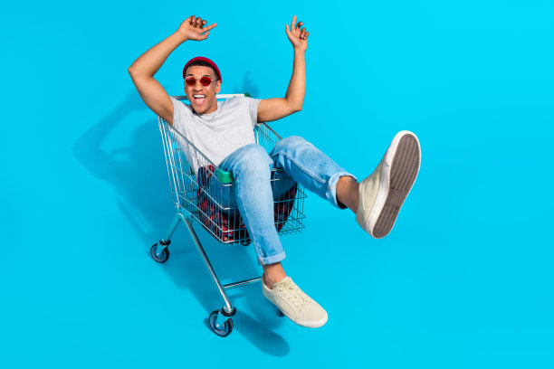 照片积极的无忧无虑的男人穿灰色t恤有乐趣骑超市托盘孤立的蓝色背景图片下载