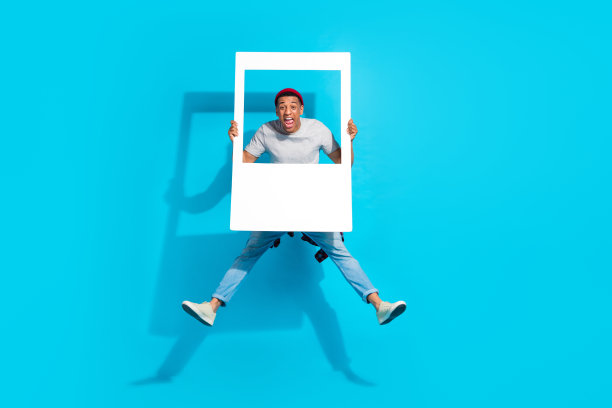 精力充沛的大喜过望的人跳跃的手臂的全长照片持有纸专辑集卡孤立的蓝色背景图片下载