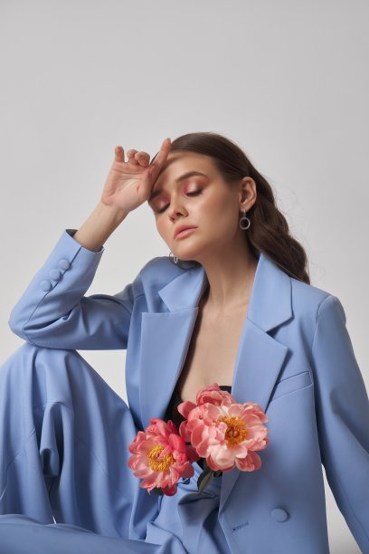 时尚女子身着蓝色西装配上粉色花朵，美颜画像。艺术工作室的肖像，一个年轻的女人在白色的背景，粉红色的化妆图片下载