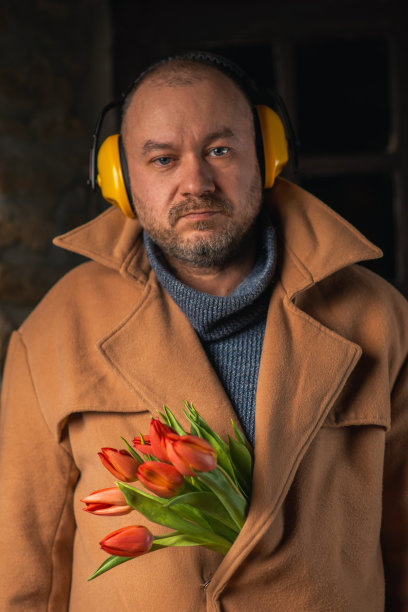 一张有趣的照片，一个人戴着耳机，外套里插着一束郁金香。图片下载