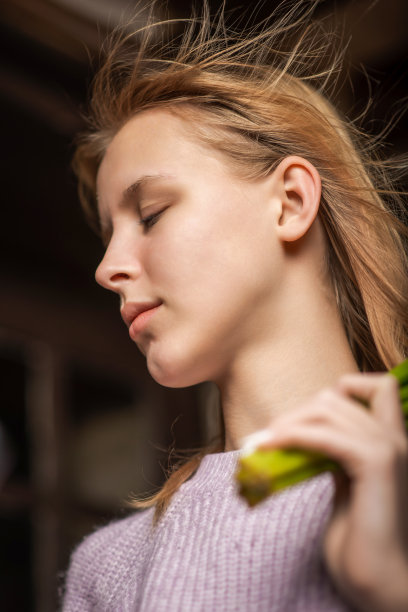 一个年轻的十几岁的女孩的肖像，她的头发飞扬，闭着眼睛，背景是黑色的。垂直的照片。图片下载