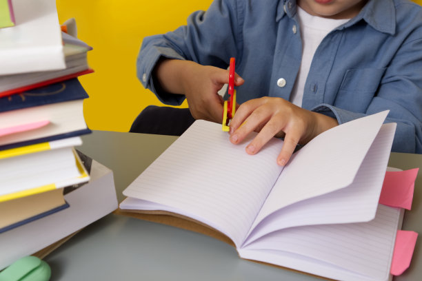 孩子坐在课桌前，近距离学习用剪刀剪东西图片下载