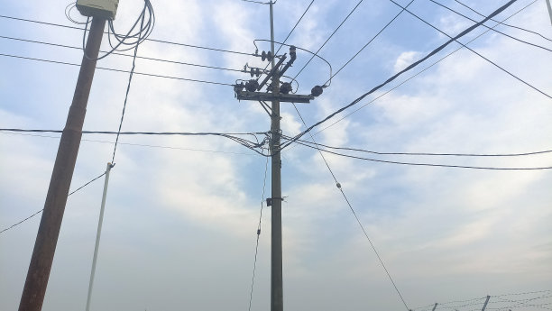 带电线电缆的电线杆。，映衬着蓝天的多云和柔和的焦点。多云天空下的电线杆，照片特写图片下载