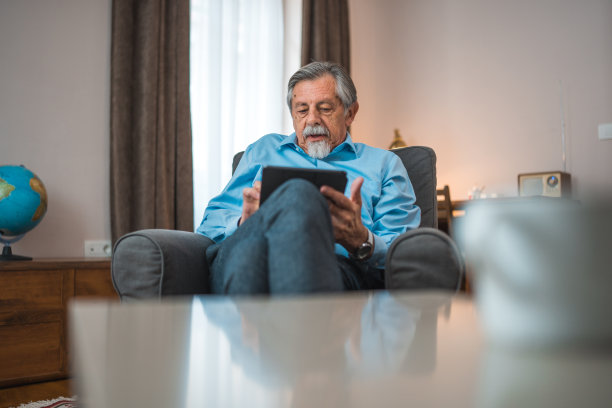 高年级白人男性在家用平板电脑看新闻图片下载