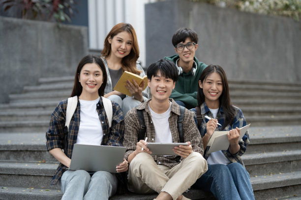 年轻的亚洲大学生坐在大学校园的楼梯上做小组项目的照片。图片下载