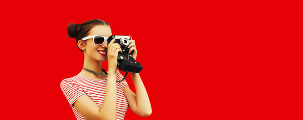 幸福的年轻女性摄影师与胶片相机的肖像，女性与凉爽的少女发型在红色背景图片下载