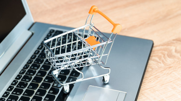 网上购物的概念。购物车或手推车和笔记本电脑放在桌子上图片下载