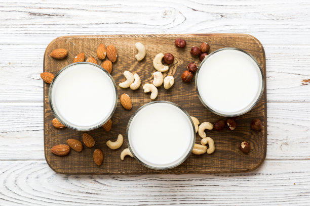 集或收集各种纯素牛奶杏仁，腰果，在桌子的背景。素食植物奶和原料，俯视图图片下载