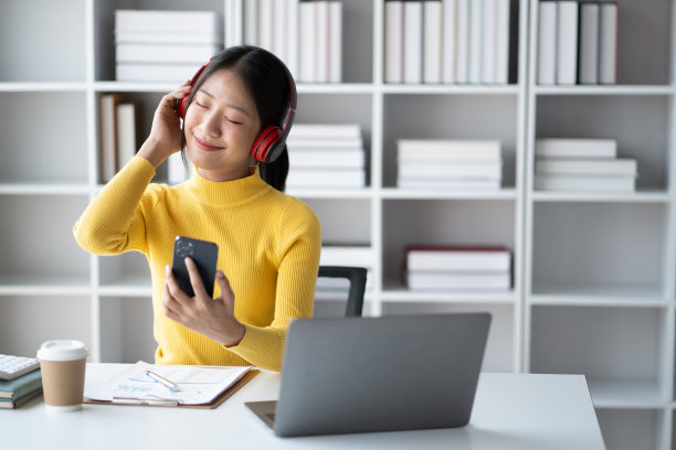 年轻漂亮的女商人喜欢在空闲时间听音乐。图片下载