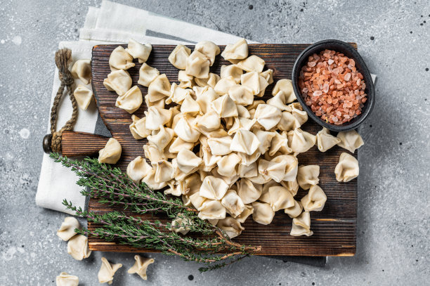 生的螳螂饺子在木板上与草药，生的食物。灰色的背景。俯视图图片下载