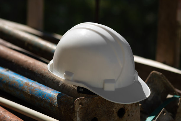 建筑工地金属结构上的白色头盔特写，安全注意事项。图片下载