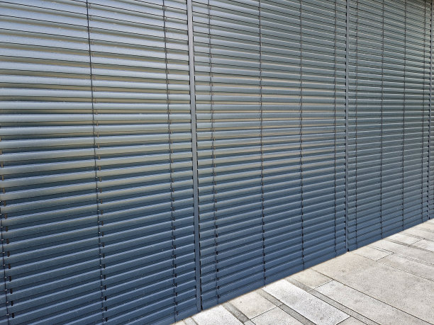 在建筑物上安装百叶窗。金属板条的调整和保养。办公室的窗户有一定角度的百叶窗。灰色金属门套。防晒、店面、服务图片下载