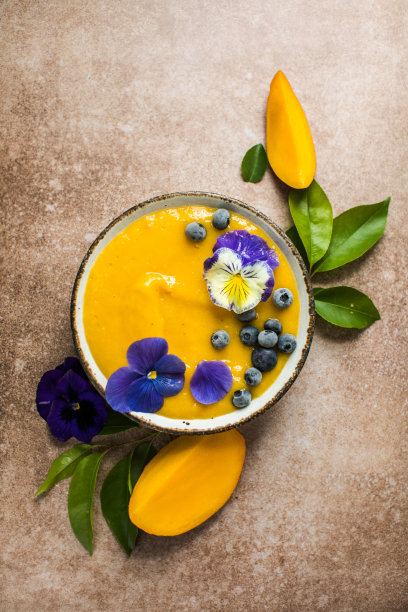 芒果汁，姜黄奶昔碗。新鲜的热带水果在浅色的背景。健康的食物图片下载