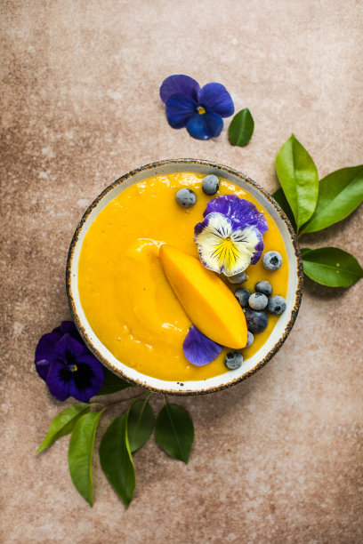 芒果汁，姜黄奶昔碗。新鲜的热带水果在浅色的背景。健康的食物图片下载