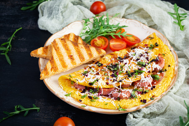 用香肠、西红柿、蔬菜和奶酪填馅的煎蛋卷。美味简单的早餐图片下载