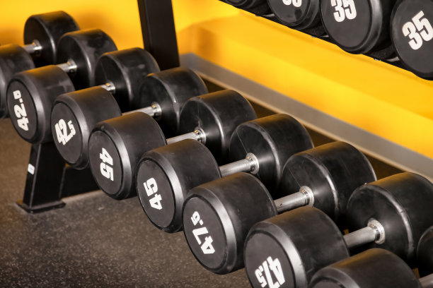 现代健身房内部与运动器材-运动哑铃架。新的健身中心库存的体育赛事和训练练习。概念运动设计背景。复制文字空间，海报图片下载