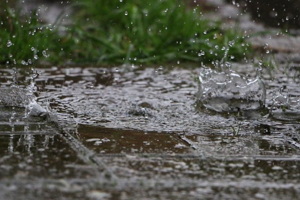一场大雨落在通往车库的车道上的一个水坑里，溅起一顶皇冠图片下载