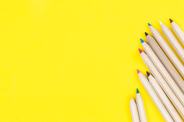 黄色背景上的彩色木铅笔，平铺。图片下载