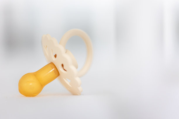 婴儿奶嘴在模糊的白色背景上。图片下载