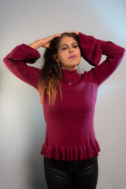 有魅力的成熟黑发女人穿着黑裤子和红衬衫，站着。工作室的照片。图片下载