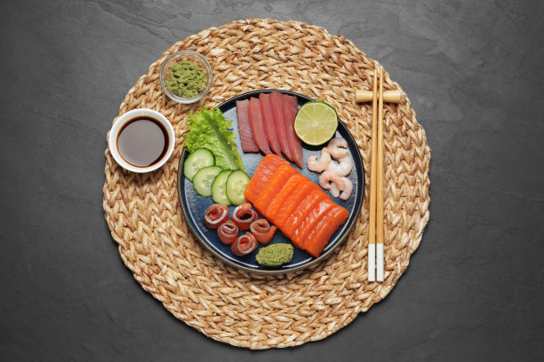 美味的鲑鱼片，虾，黄瓜和金枪鱼在黑色的桌子上，俯视图。美味的生鱼片图片下载