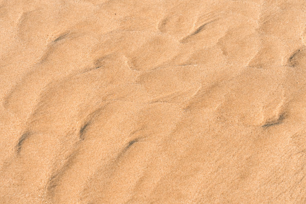 沙子纹理背景在夏天，沙丘沙波浪图案。沙滩沙滩表面与波浪涟漪的海水与复制空间为夏季横幅设计，天然棕色黄沙石头在海边图片下载