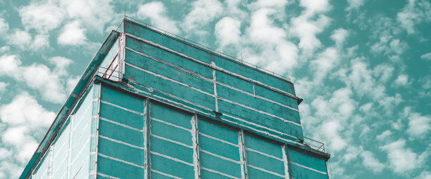 多层生产大楼的巨大墙壁。风景如画的经过翻新的老工厂。老旧的工业物件。大型制造业高层建筑立面。工业区特写。多云的天空。图片下载