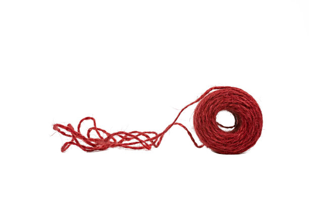 用红绳织造的线轴在白色的背景上有点不受伤害。图片下载