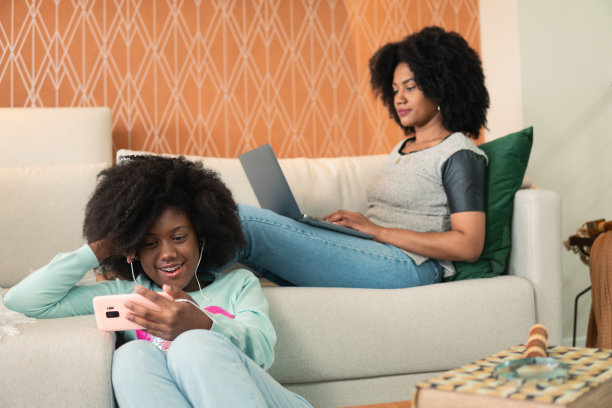 女儿用手机看视频，母亲在工作图片下载