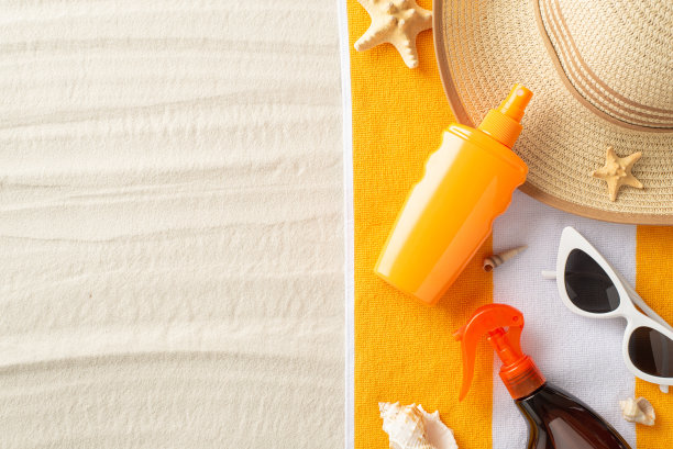 防晒度假概念。沙滩毛巾，草帽，防晒喷雾，太阳镜与海洋贝壳和海星在沙滩上孤立的背景与copyspace的俯视图照片图片下载