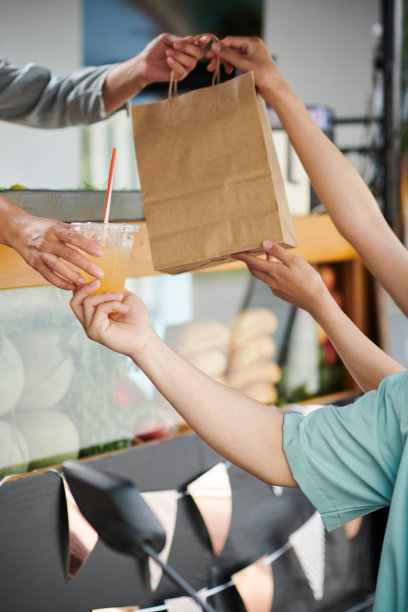 年轻夫妇的手拿着装着外卖食品和一杯果汁的纸袋图片下载