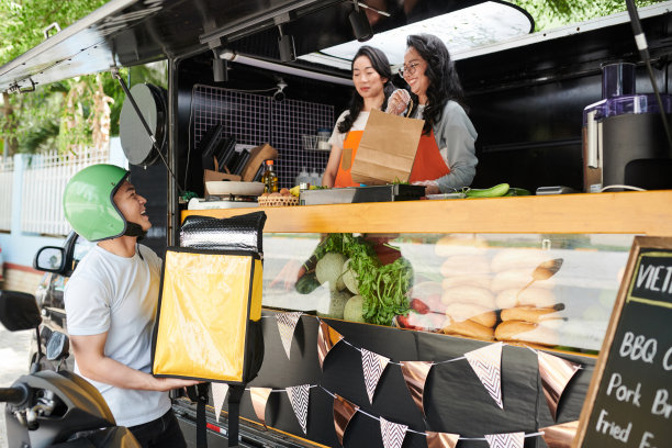 穿着制服的年轻女人微笑着拿着纸袋看着快递员图片下载