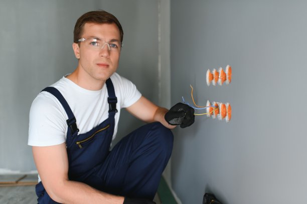 穿制服的电工在室内白墙上安装插座图片下载