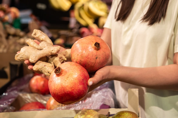 在商店或市场上，妇女手持石榴，近距离观看。图片下载