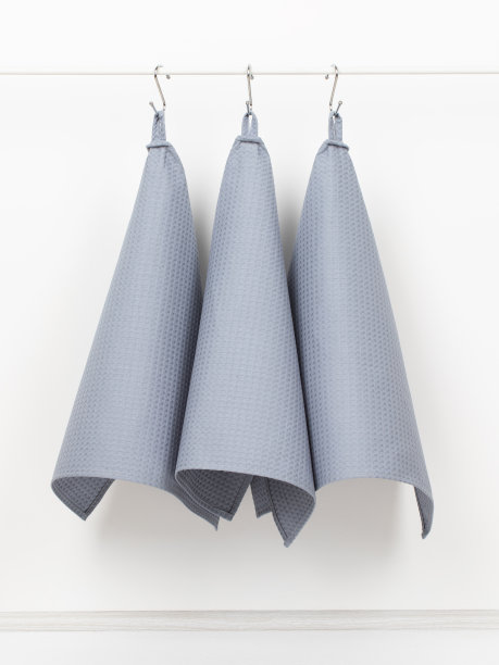 厨房用的棉质华夫饼毛巾挂在支架上的挂钩上，背景是白色的墙壁图片下载