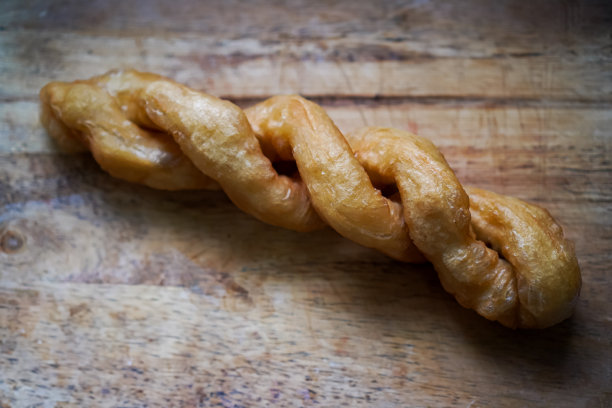 一张特写照片显示了一个大螺旋形的油炸油条，上面放着豆浆。图片下载