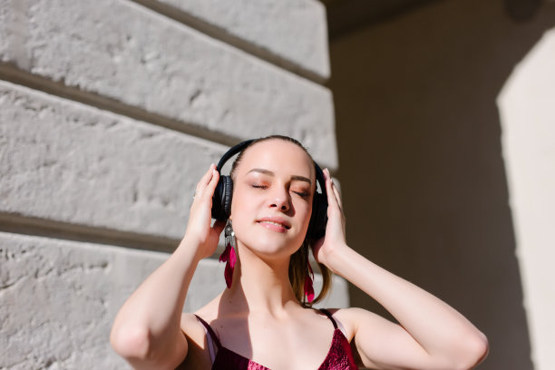 快乐的女人在城市里戴着耳机听音乐图片下载