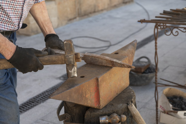 用锤子把热金属锻造成一把刀——用钳子夹住刀图片下载